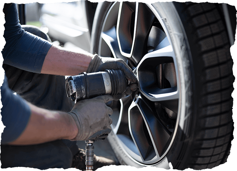 A professional using a tool on a car wheel for tire services in Calgary, CA.