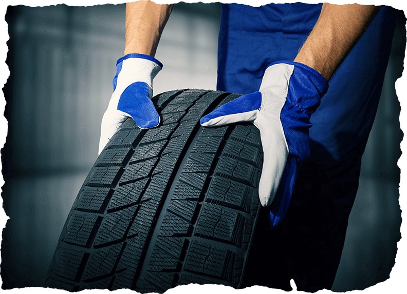 Mechanic holding a new tyre in the garage background at the Tire Pirates in Calgary, AB