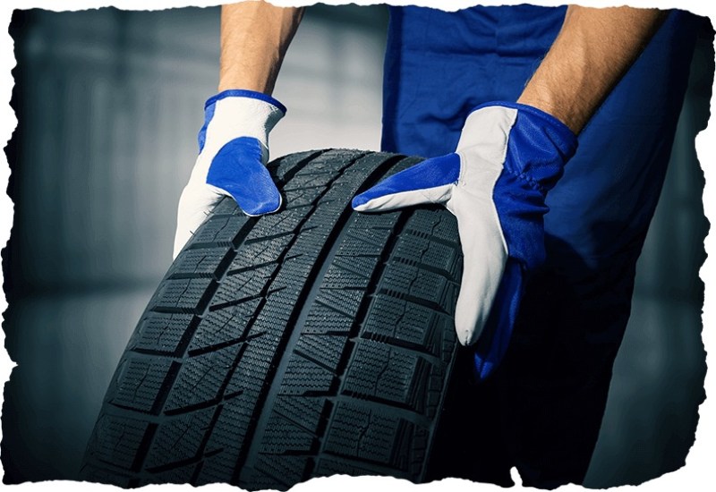 Mechanic holding a new tyre in the garage background at the Tire Pirates in Calgary, AB